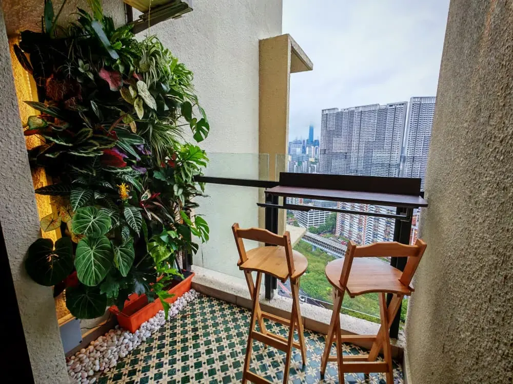 Same balcony in 2026 with a vertical plant wall, patterned floor tiles and bar seating