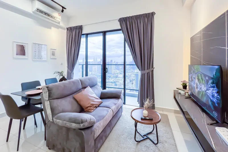 Living room with full-height windows in the owner-furnished 2-bedroom Trion KL unit